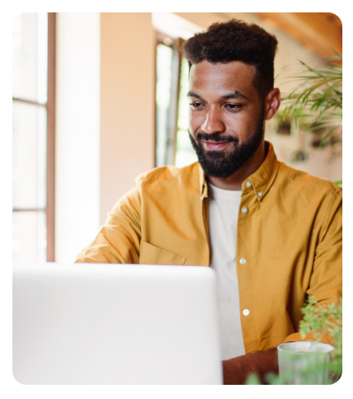 Young man with laptop and coffee working indoors, home office